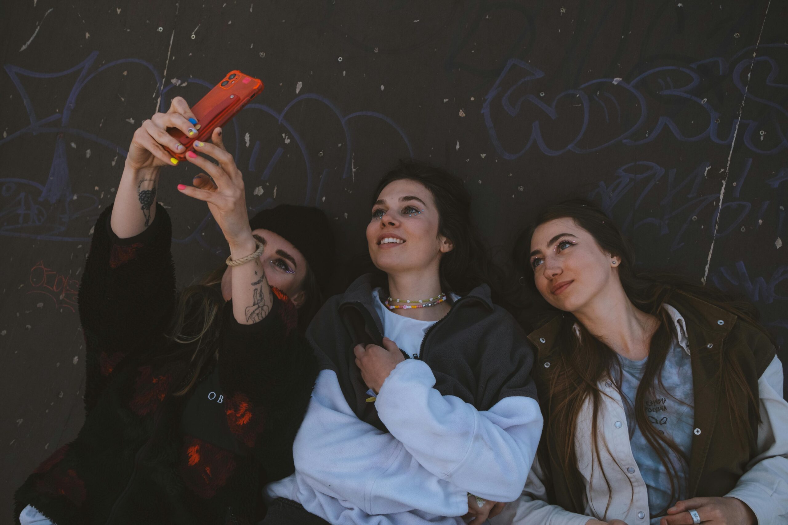 Three friends capturing a fun moment with a selfie on their mobile phone.